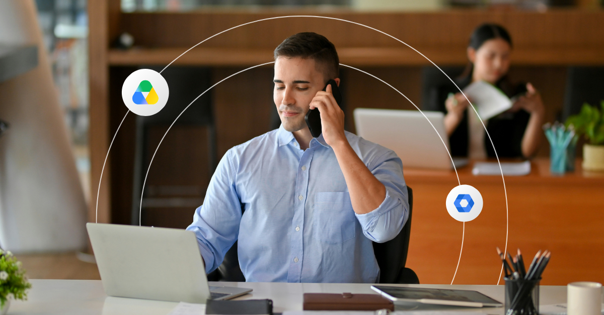 A professional looking man smiles at his laptop screen while on the phone 