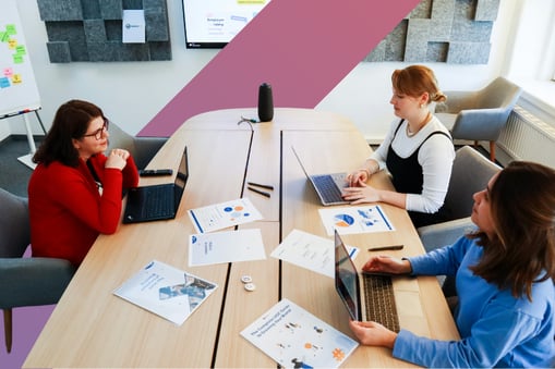 Three women chat around a large conference table 