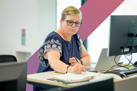 A professional woman works at a standing desk